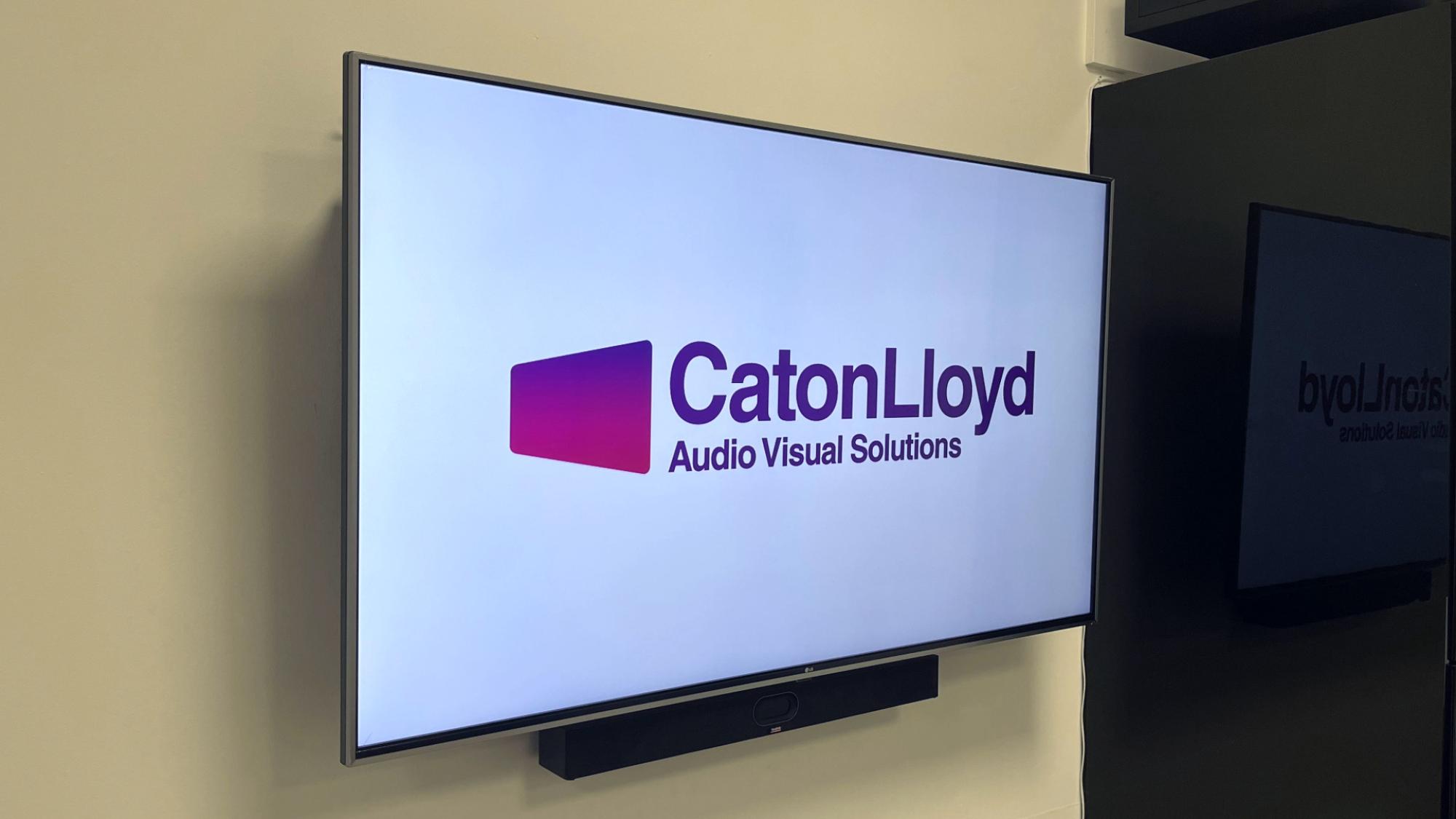 Screen displaying CatonLloyds logo and a Yealink all-in-one conferencing camera below it in a small office space meeting room