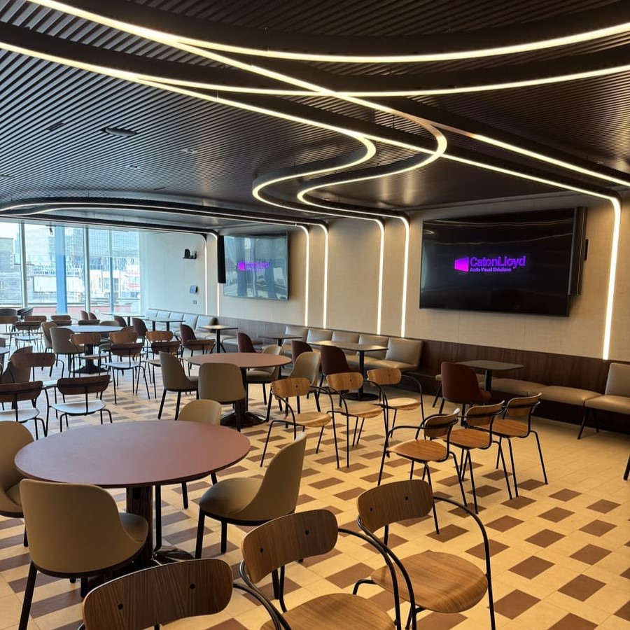 Teamwork, presentation and collaboration space in CoStar Groups office in London, with many tables and chairs, LED lighting and two 98 inch screens