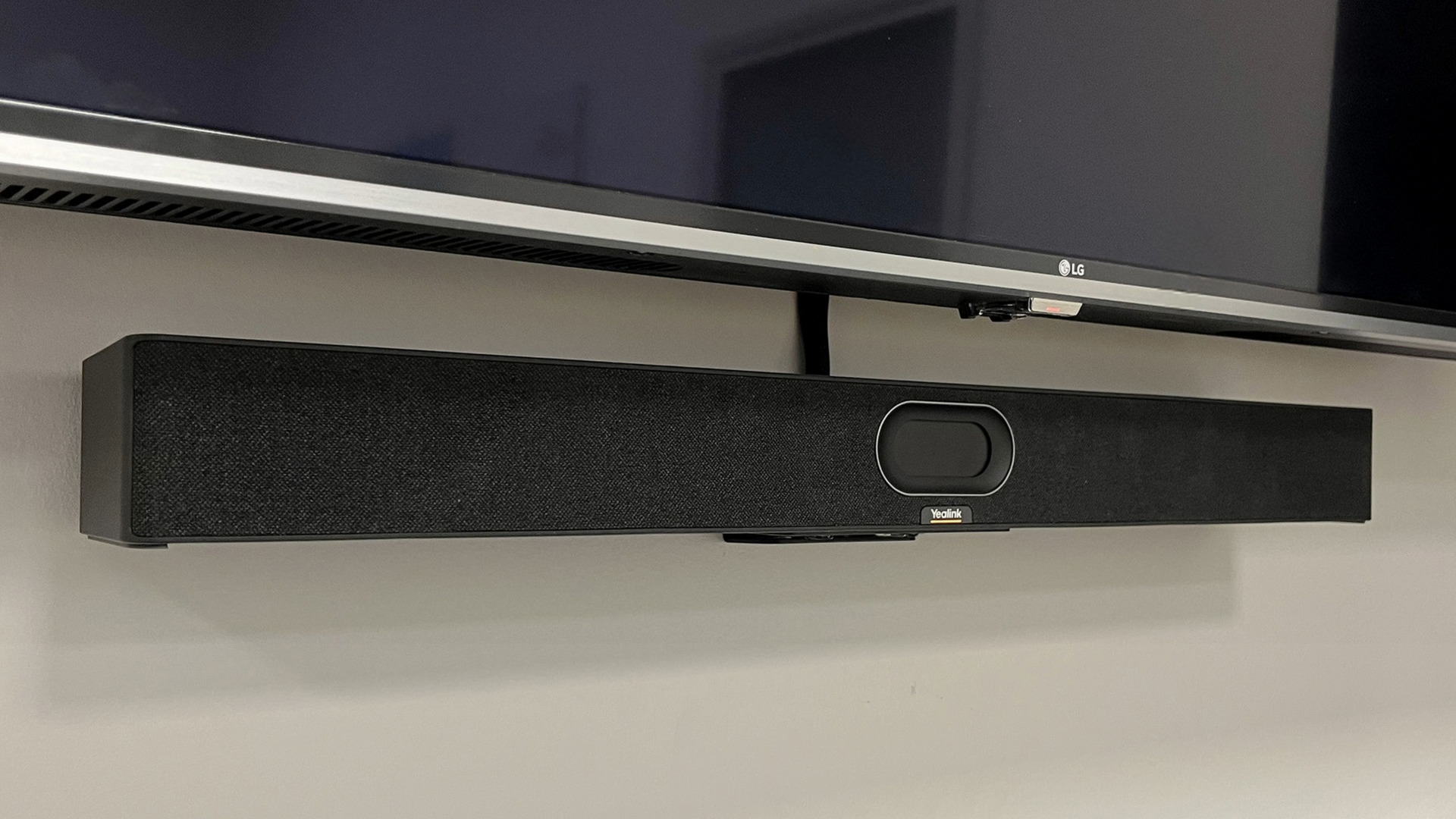 Yealink SmartVision 40 conference camera attached to a wall under a display screen in a small meeting room