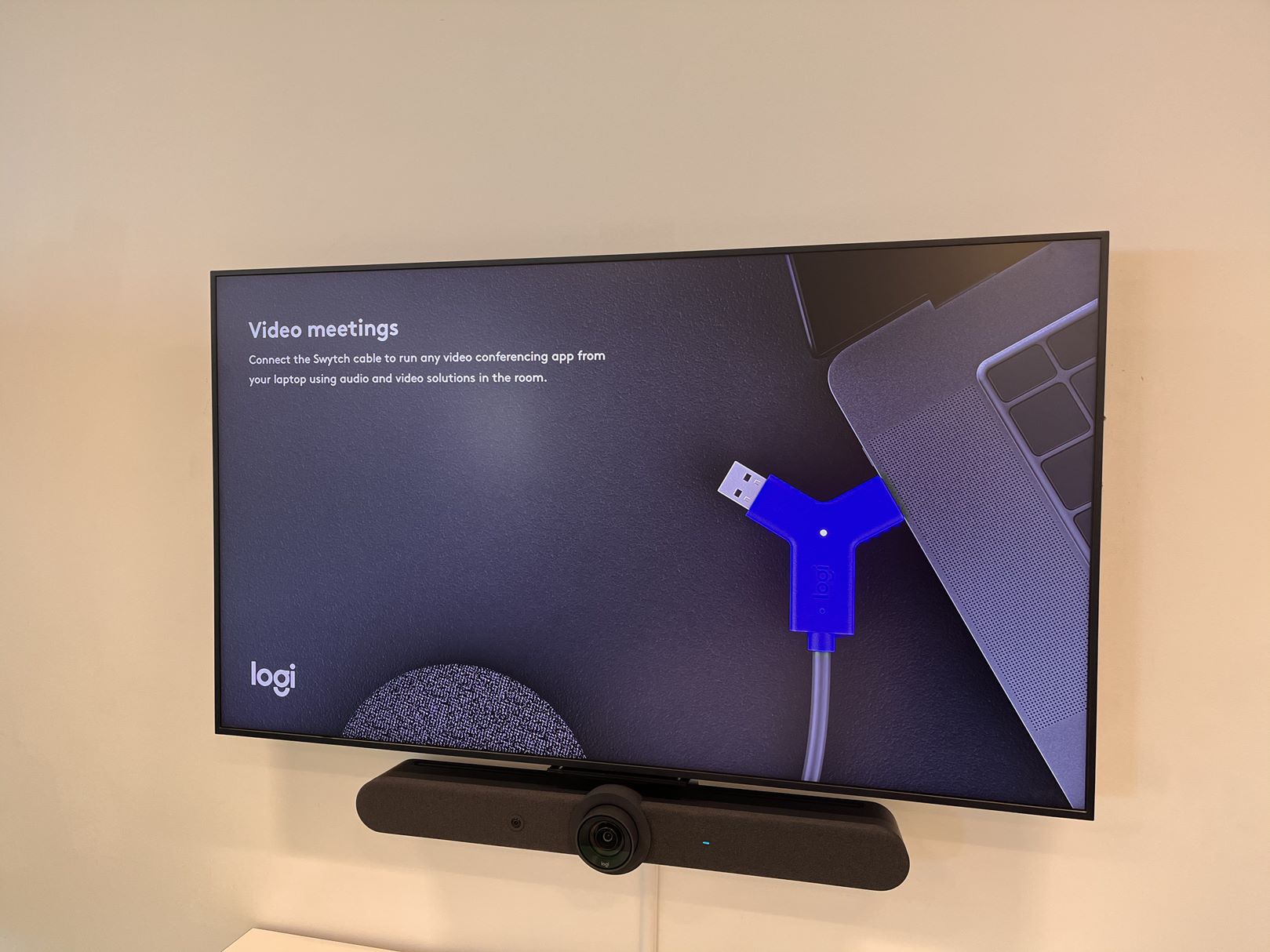 Large display screen installed inside of London meeting room with soundbar and webcam.